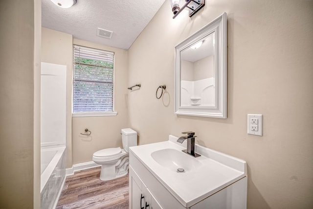 full bath featuring visible vents, toilet, wood finished floors, a textured ceiling, and vanity