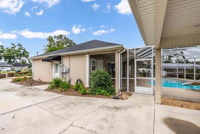 561 Sevilla Spring Cir, Lake Park, GA 31636 - back of property with a patio, an outdoor pool, stucco siding, roof with shingles, and glass enclosure