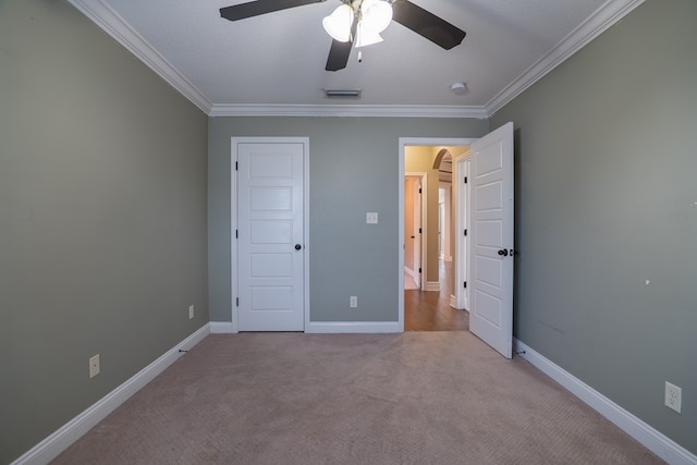 unfurnished bedroom with ornamental molding, light carpet, a textured ceiling, and ceiling fan