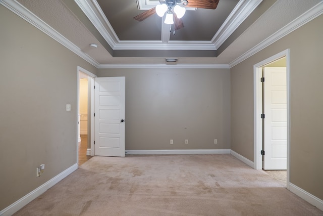 empty room with ceiling fan, ornamental molding, a raised ceiling, and light carpet