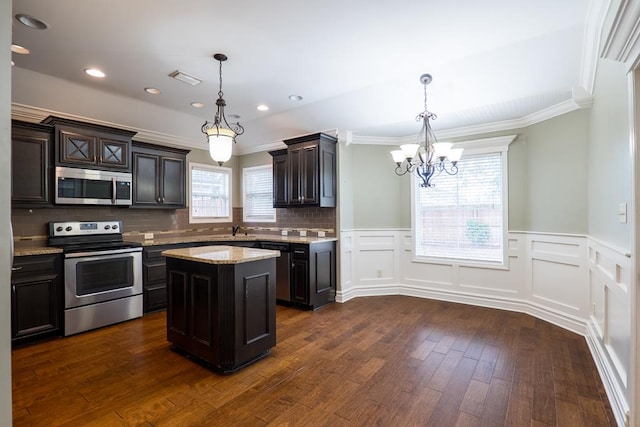 kitchen with a kitchen island, appliances with stainless steel finishes, dark wood-type flooring, and decorative light fixtures