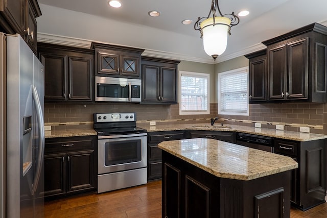 kitchen featuring sink, appliances with stainless steel finishes, decorative backsplash, a kitchen island, and decorative light fixtures