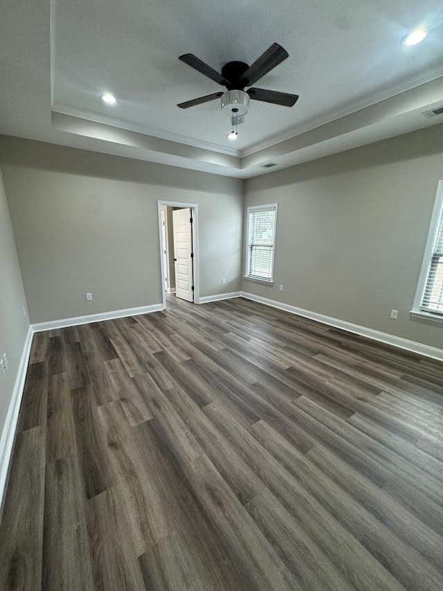 empty room with dark hardwood / wood-style floors, ornamental molding, and a raised ceiling