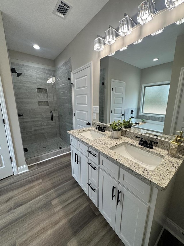 bathroom with vanity, a textured ceiling, plus walk in shower, and hardwood / wood-style floors