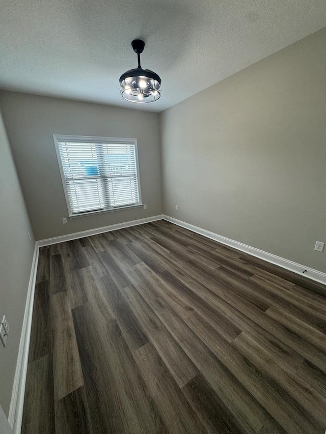 unfurnished room featuring dark hardwood / wood-style floors, a textured ceiling, and a notable chandelier