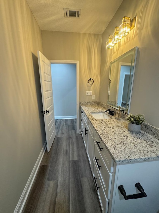 bathroom featuring hardwood / wood-style floors, vanity, a textured ceiling, and an inviting chandelier