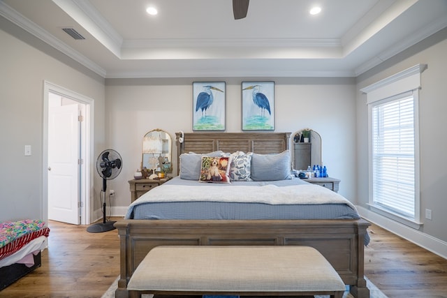 bedroom with a raised ceiling, ceiling fan, ornamental molding, and hardwood / wood-style flooring