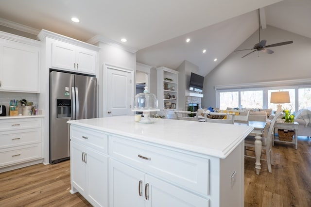 kitchen with white cabinetry, ceiling fan, stainless steel fridge, a kitchen island, and hardwood / wood-style flooring