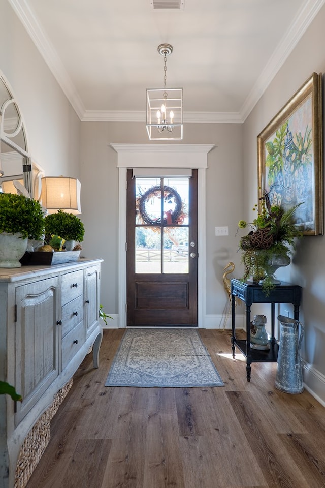 foyer featuring wood-type flooring, crown molding, and an inviting chandelier