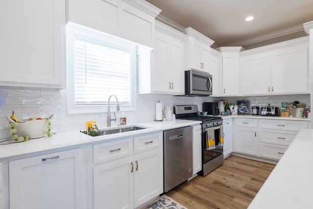 kitchen featuring sink, stainless steel appliances, tasteful backsplash, white cabinets, and ornamental molding