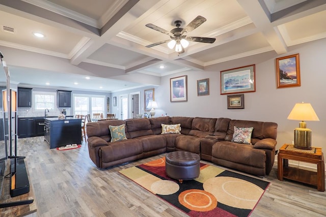 living room with beamed ceiling, light hardwood / wood-style floors, sink, ceiling fan, and coffered ceiling