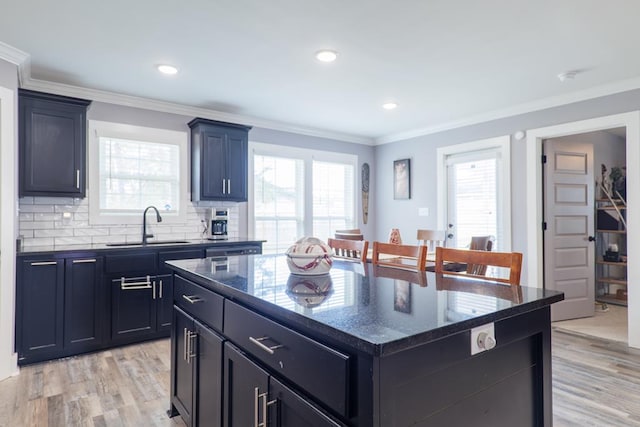 kitchen with crown molding, sink, light wood-type flooring, a center island, and decorative backsplash