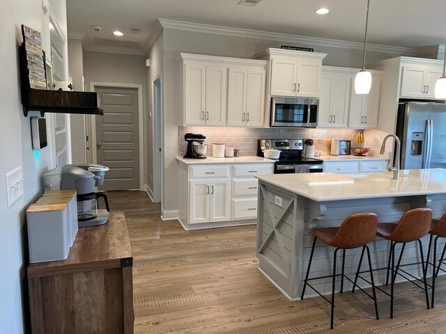 kitchen featuring a kitchen island with sink, white cabinets, light hardwood / wood-style floors, and appliances with stainless steel finishes