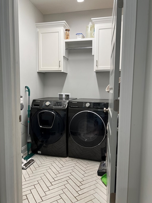 clothes washing area with washer and dryer and cabinets