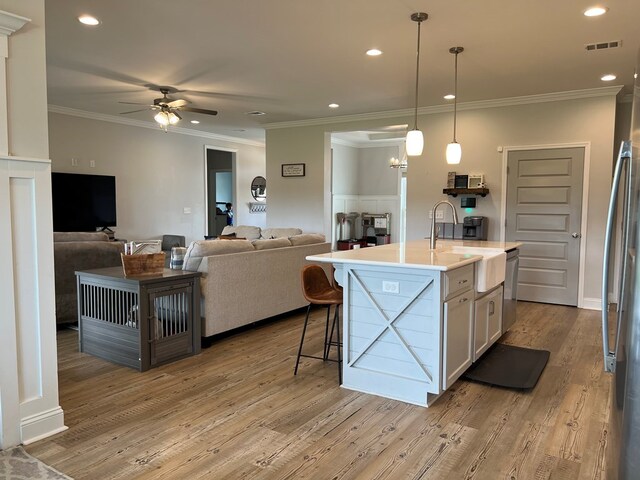 kitchen featuring pendant lighting, a kitchen island with sink, white cabinets, sink, and ceiling fan