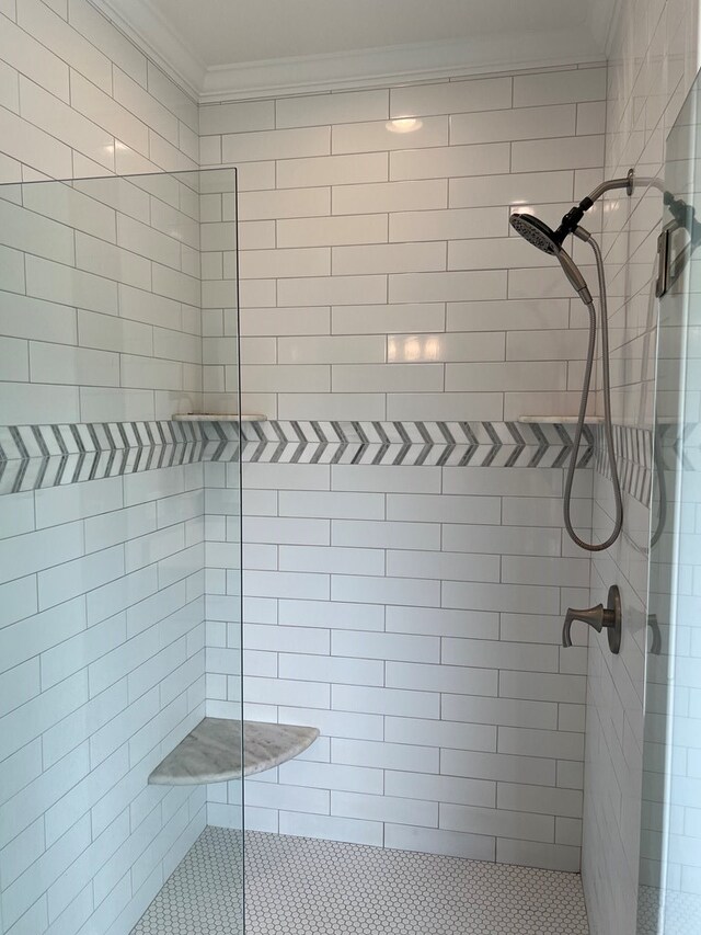 bathroom with tiled shower and crown molding