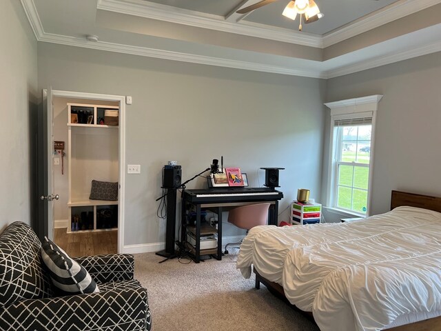 bedroom with carpet floors, a raised ceiling, ceiling fan, and ornamental molding