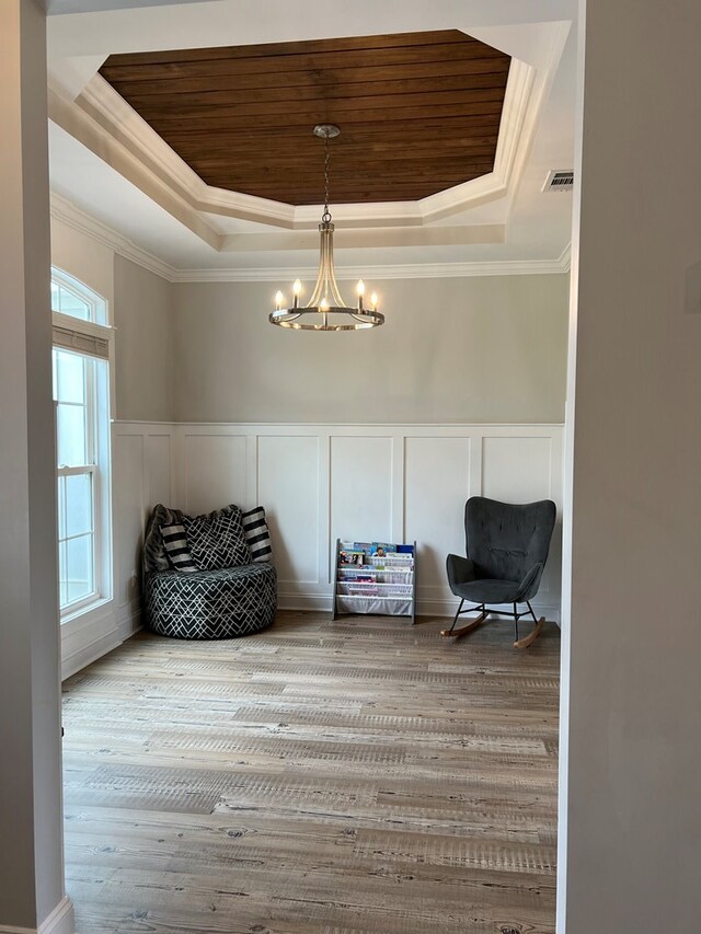 sitting room featuring a notable chandelier, ornamental molding, a tray ceiling, and light hardwood / wood-style flooring