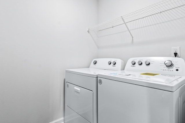 clothes washing area featuring washing machine and dryer, laundry area, and baseboards