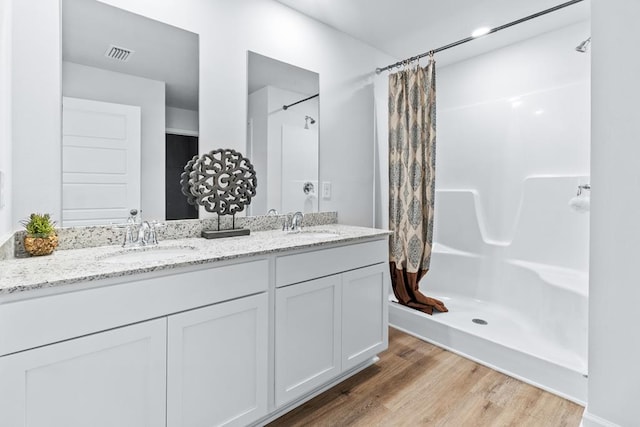 full bath with a shower with shower curtain, a sink, and visible vents