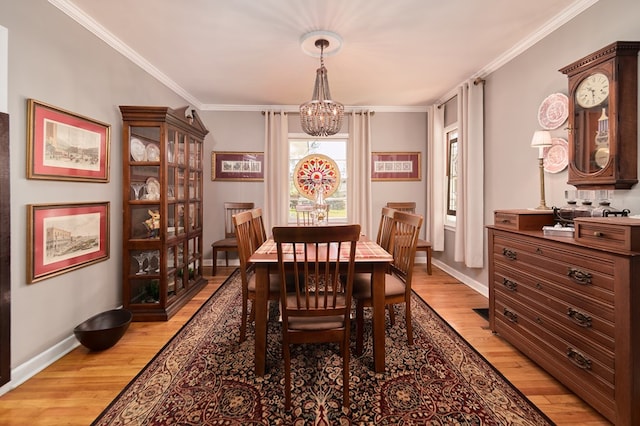 dining area featuring crown molding, a notable chandelier, and light wood-type flooring