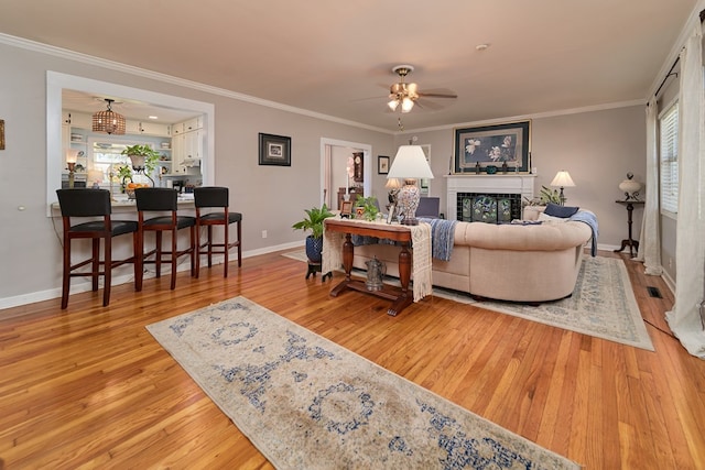 living room with ornamental molding, ceiling fan, and light hardwood / wood-style floors