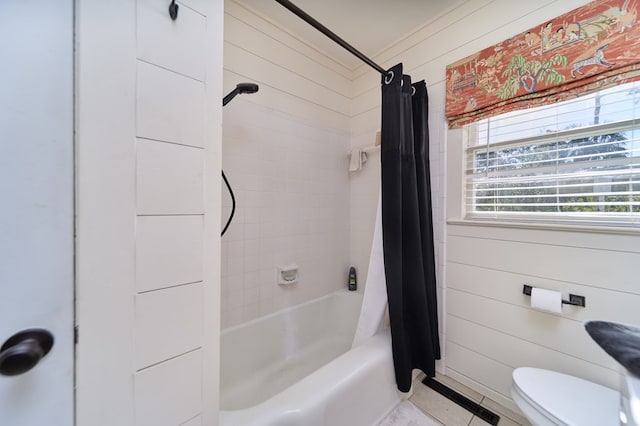 bathroom featuring wooden walls, shower / bath combination with curtain, and toilet