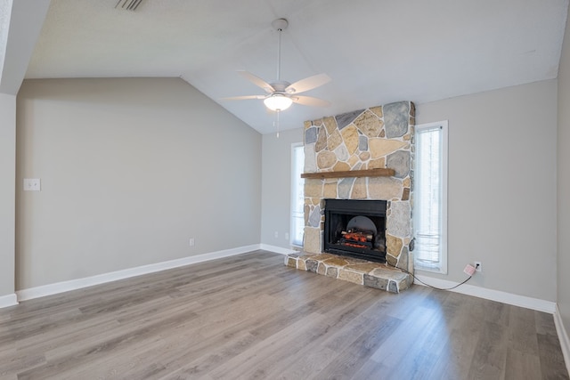 unfurnished living room with ceiling fan, a fireplace, lofted ceiling, and light wood-type flooring