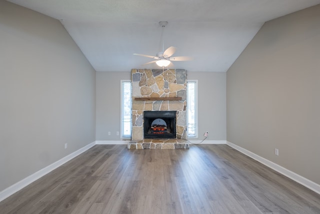 unfurnished living room featuring a stone fireplace, ceiling fan, wood-type flooring, and vaulted ceiling