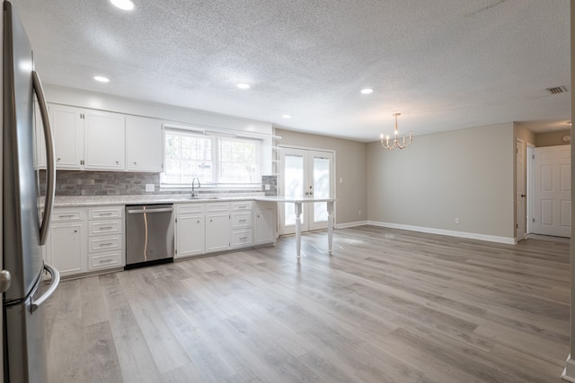 kitchen featuring french doors, appliances with stainless steel finishes, tasteful backsplash, light hardwood / wood-style floors, and white cabinetry