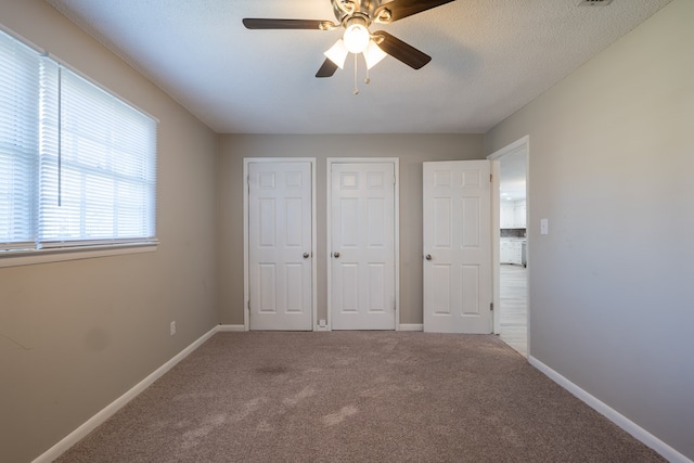 unfurnished bedroom with carpet, ceiling fan, and a textured ceiling