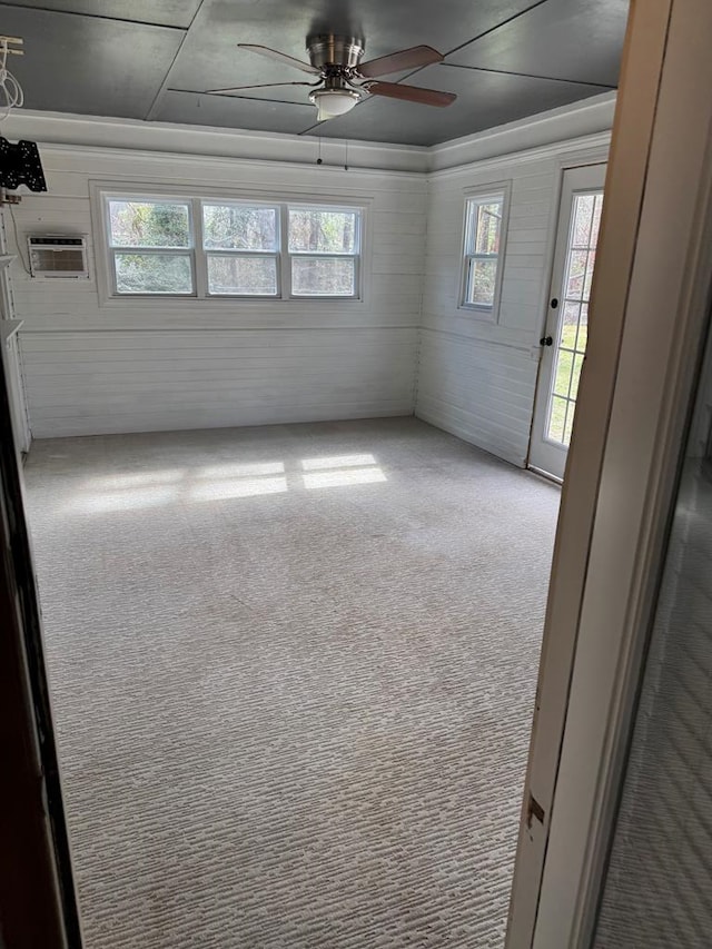 carpeted empty room featuring a healthy amount of sunlight, ceiling fan, and an AC wall unit