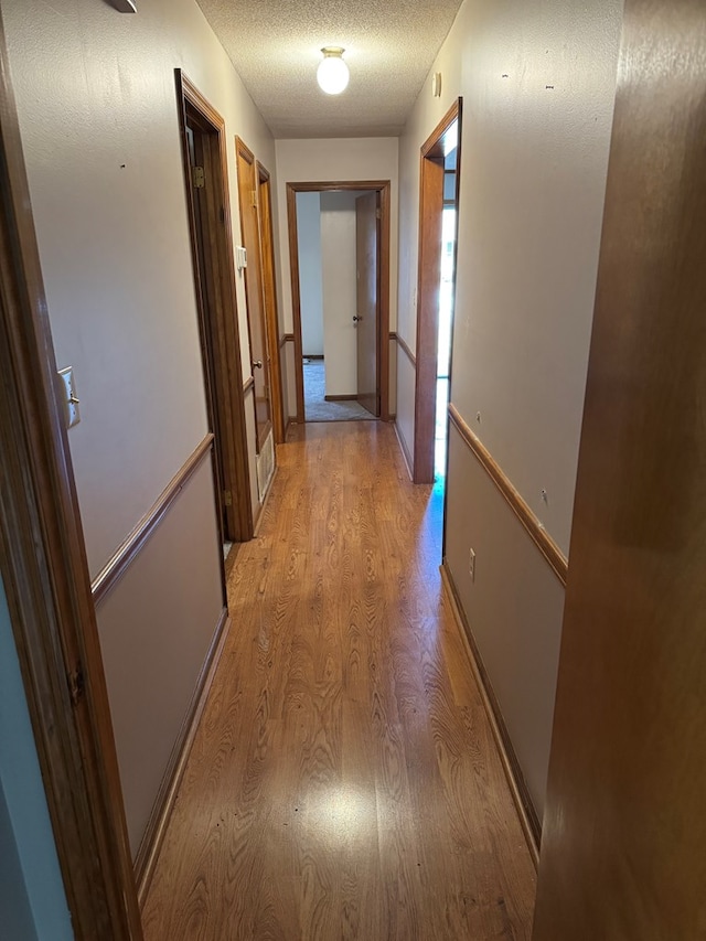 hallway featuring a textured ceiling and light wood-style floors