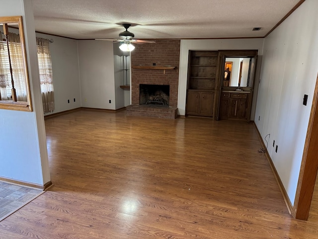 unfurnished living room featuring visible vents, ceiling fan, wood finished floors, crown molding, and a textured ceiling