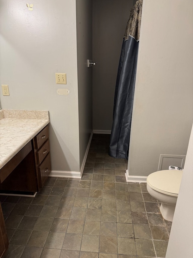 bathroom with toilet, vanity, and baseboards