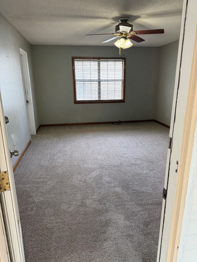 carpeted spare room with a ceiling fan, a textured ceiling, and baseboards