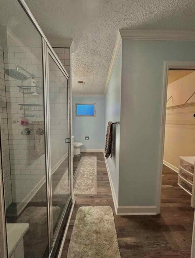 509 S Nelson St, Hahira, GA 31632 - full bathroom with ornamental molding, a textured ceiling, wood finished floors, a shower stall, and a walk in closet