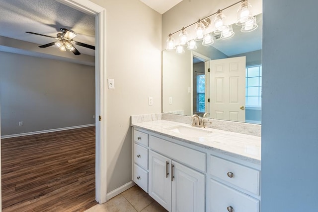 bathroom with ceiling fan, vanity, wood-type flooring, and a textured ceiling