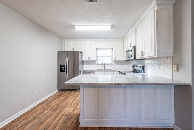 kitchen with kitchen peninsula, stainless steel appliances, white cabinetry, and sink