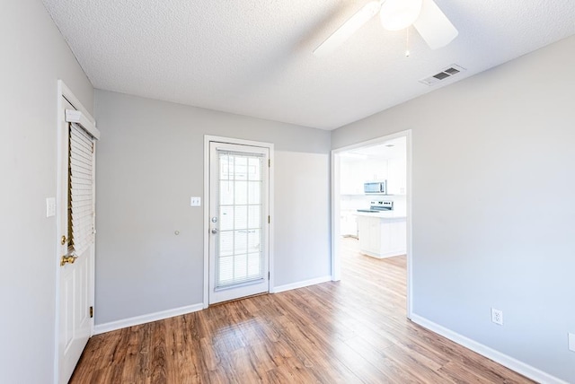 interior space with ceiling fan, a textured ceiling, and light wood-type flooring