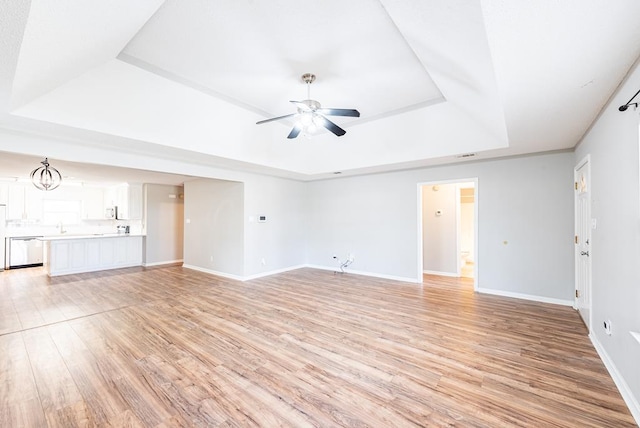 unfurnished living room featuring a raised ceiling, ceiling fan, and light hardwood / wood-style flooring