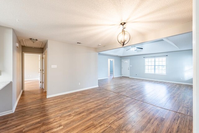 spare room with hardwood / wood-style floors, ceiling fan with notable chandelier, and a textured ceiling