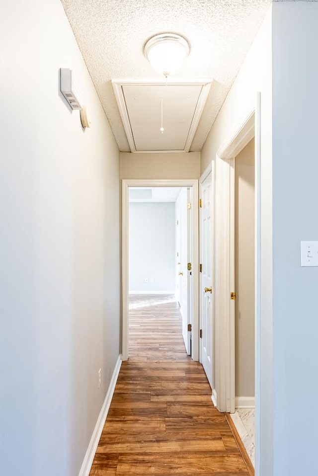 corridor with a textured ceiling and dark wood-type flooring