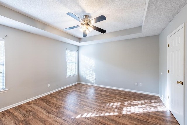 unfurnished room with hardwood / wood-style flooring, ceiling fan, a textured ceiling, and a tray ceiling