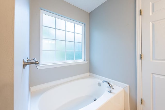 bathroom featuring plenty of natural light, a bath, and a textured ceiling