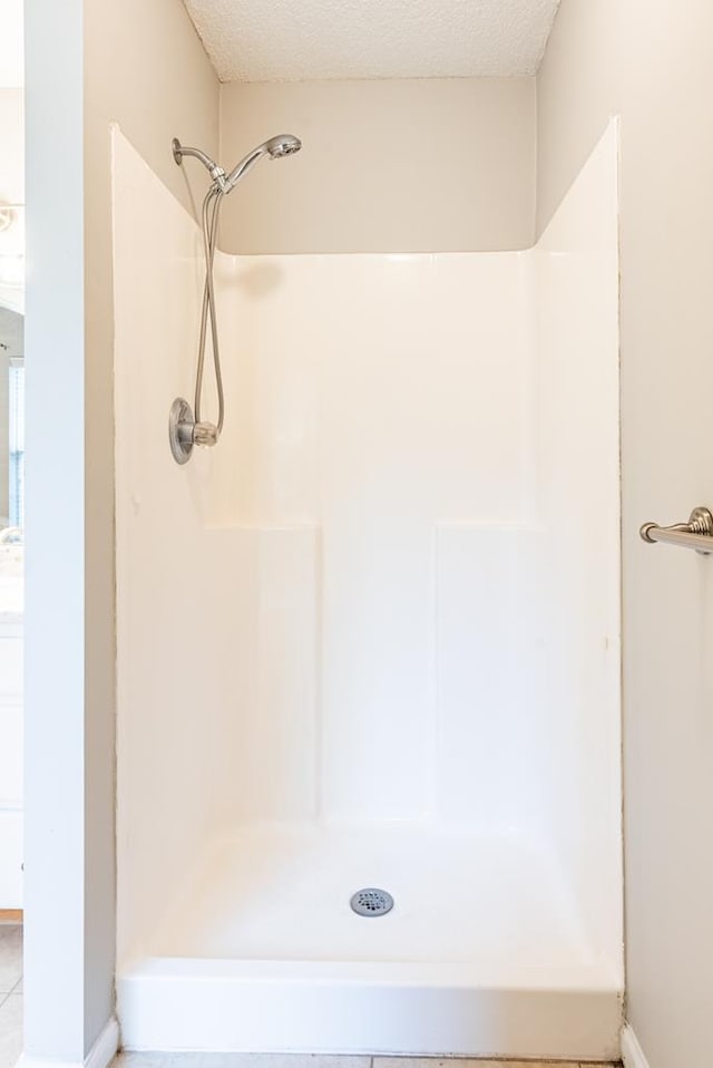 bathroom featuring a textured ceiling, tile patterned floors, and walk in shower