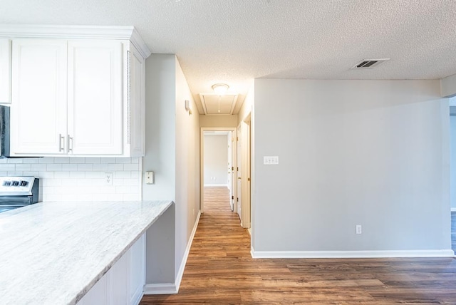 corridor with a textured ceiling and dark hardwood / wood-style flooring