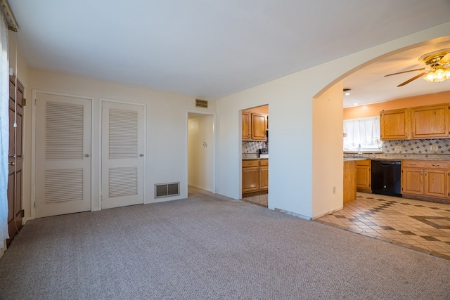 kitchen featuring tasteful backsplash, light colored carpet, ceiling fan, sink, and black dishwasher