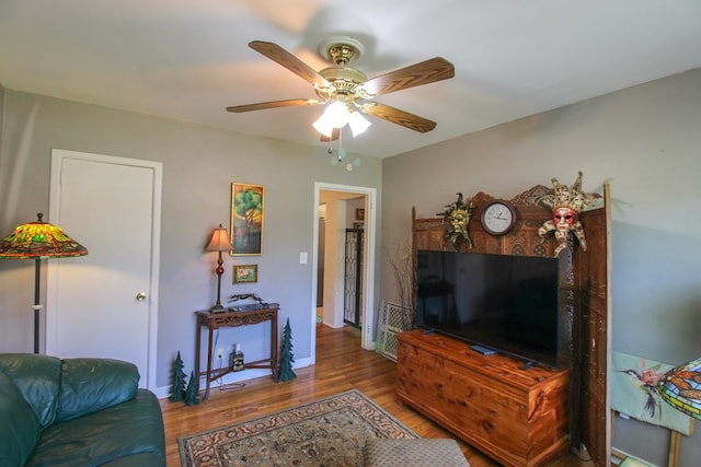 living area with baseboards, a ceiling fan, and wood finished floors