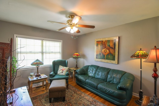 living room with a ceiling fan, baseboards, and wood finished floors